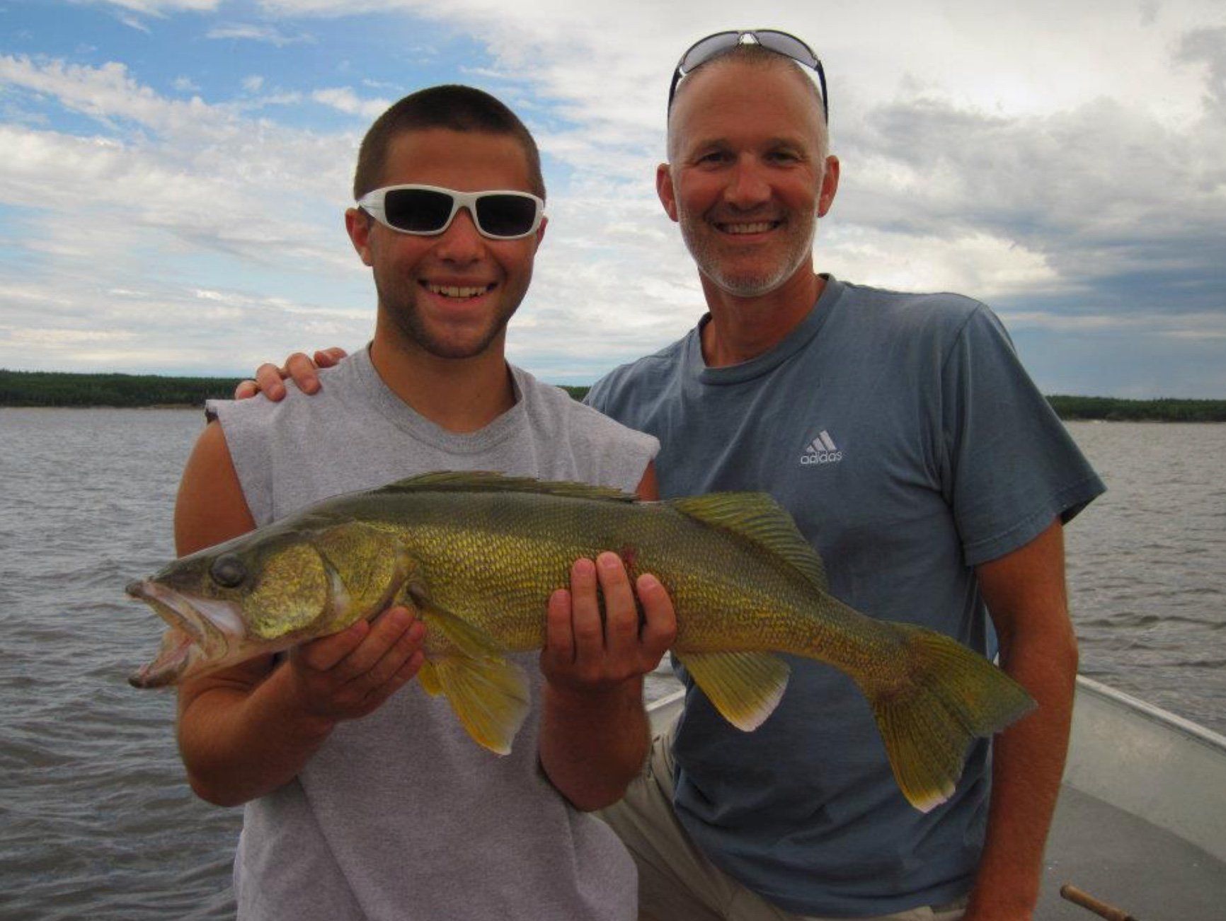 Father and son with a walleye while fishing in Canada.