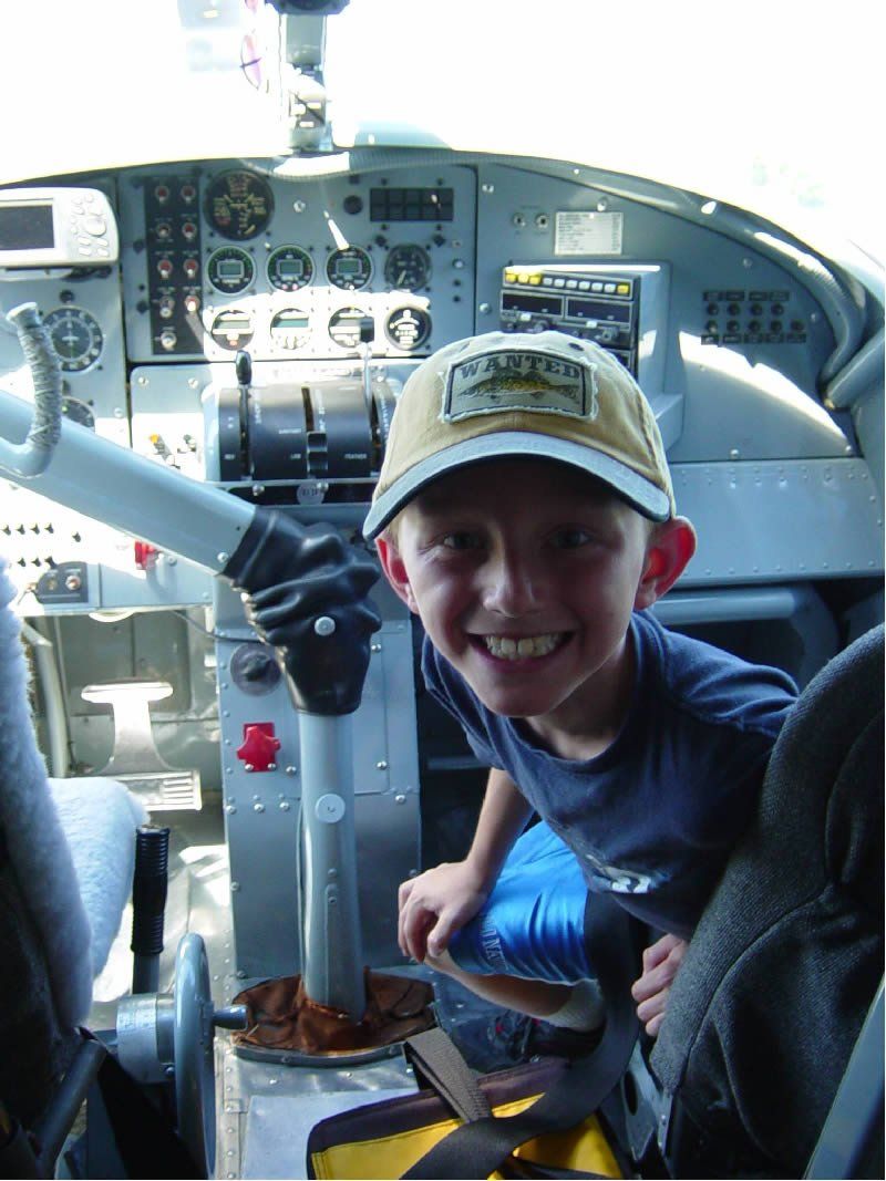 A boy sitting up front with the pilot of the float plane.