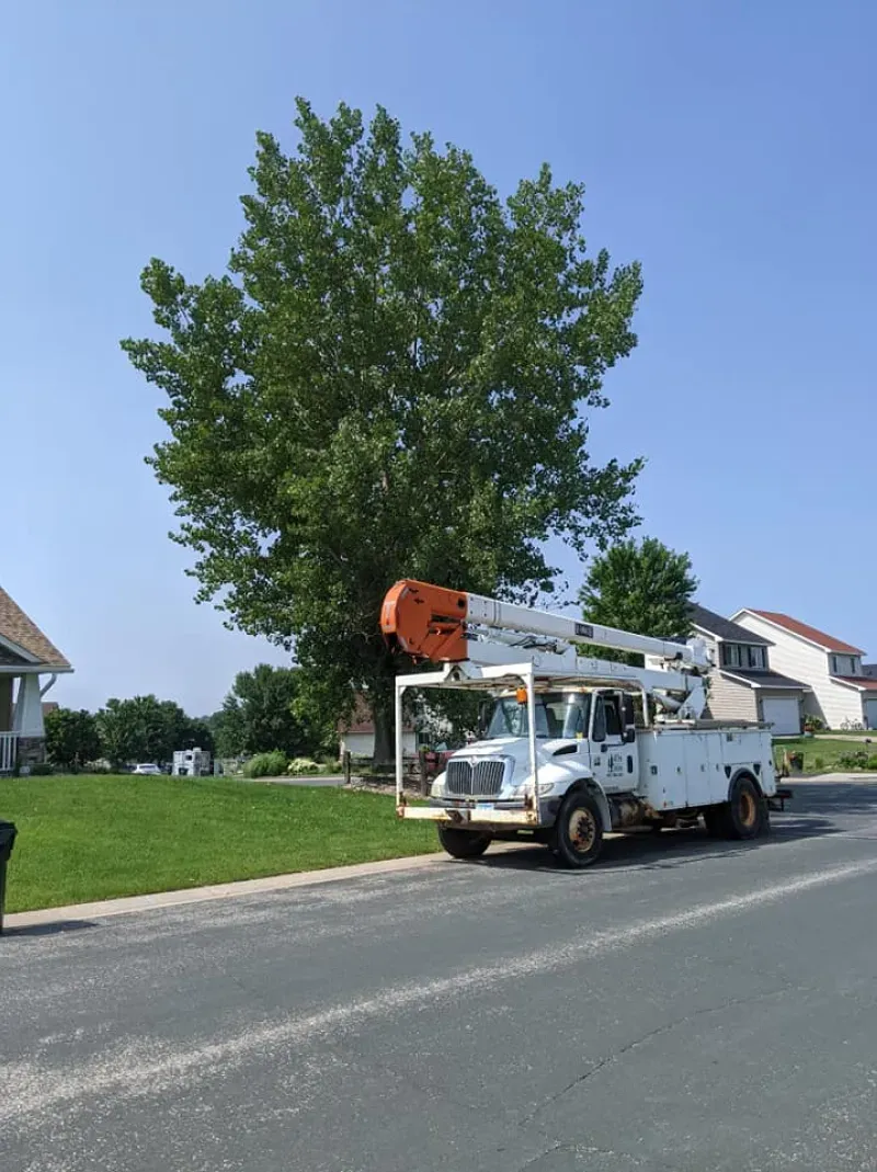 A white truck with a crane on top of it is driving down a street.