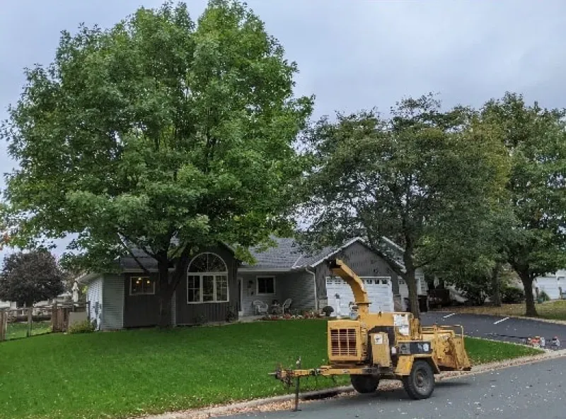 A tree chipper is parked in front of a house