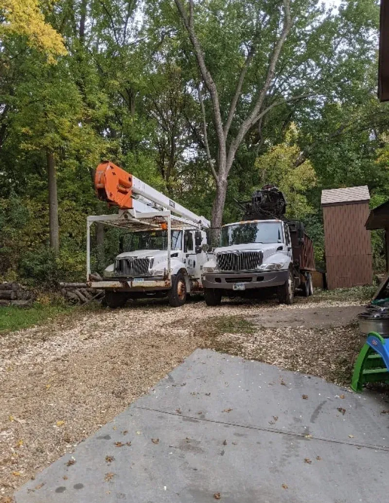 Two trucks are parked on the side of a dirt road.