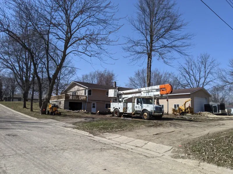 A white truck with a crane on top of it is parked in front of a house.