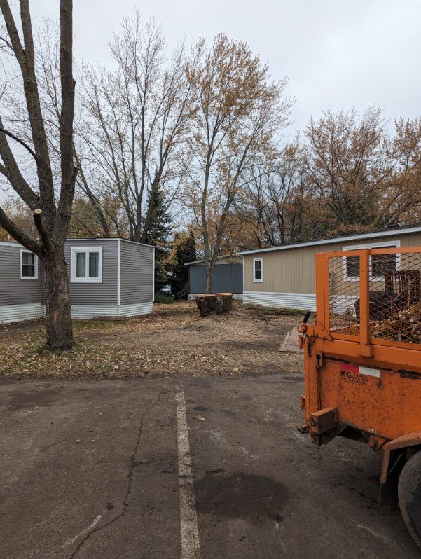 An orange truck is parked in a parking lot in front of a mobile home.