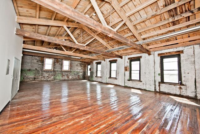 a large empty room with wooden floors and a wooden ceiling .
