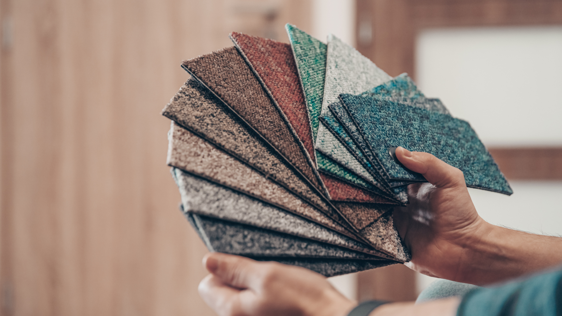 A person is holding a fan of carpet samples in their hands.