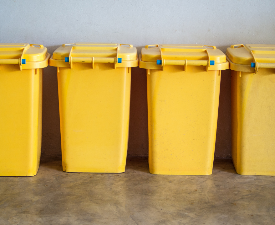 A row of yellow trash cans sitting next to each other on a concrete floor.