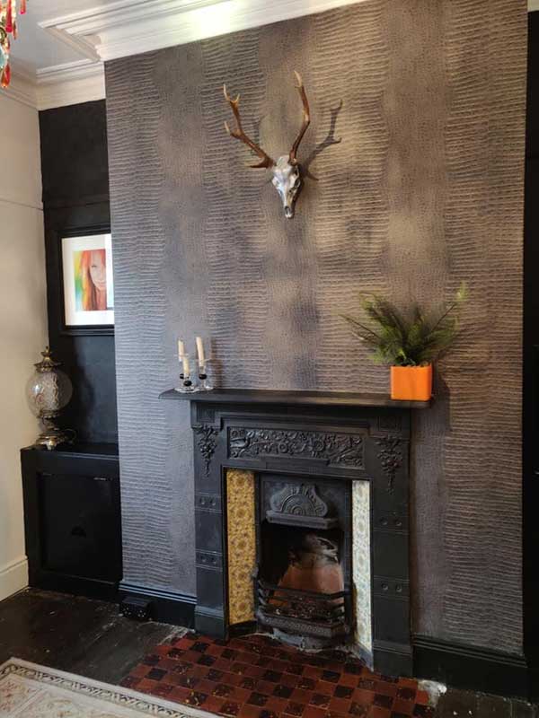 Black fireplace, gold patterned wallpaper; contemporary