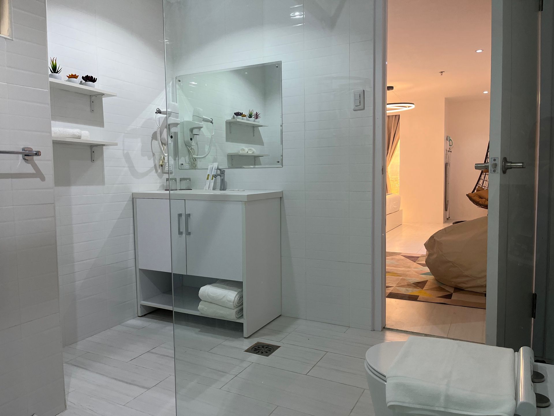 A bathroom with a toilet , sink , mirror and walk in shower.