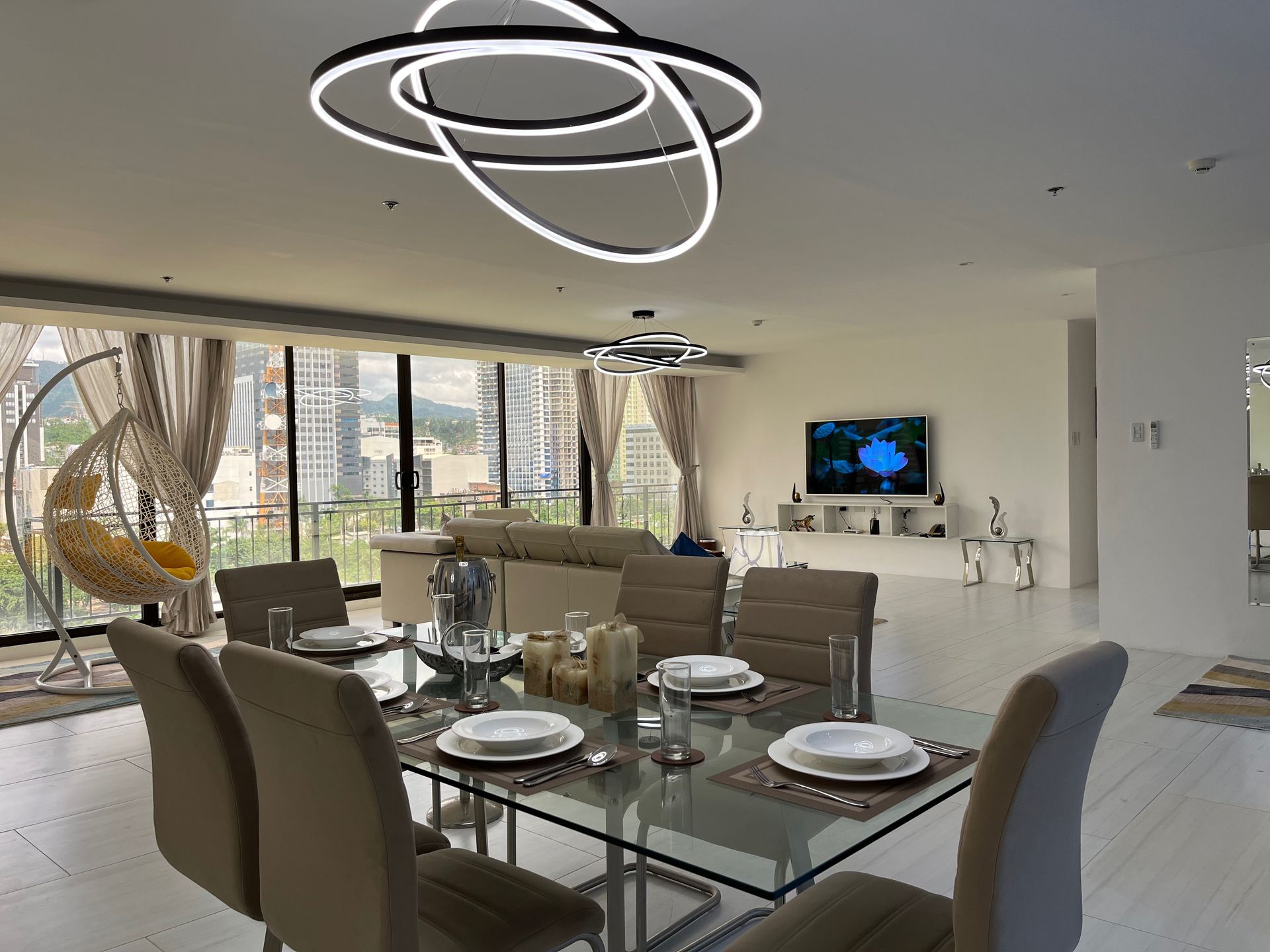 A dining room with a glass table and chairs and a television.