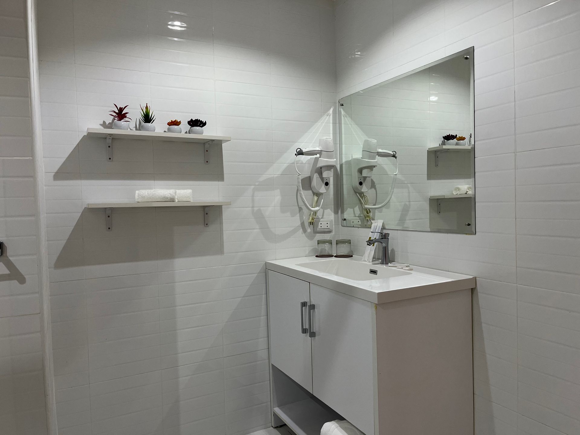 A bathroom with a sink , mirror and shelves.