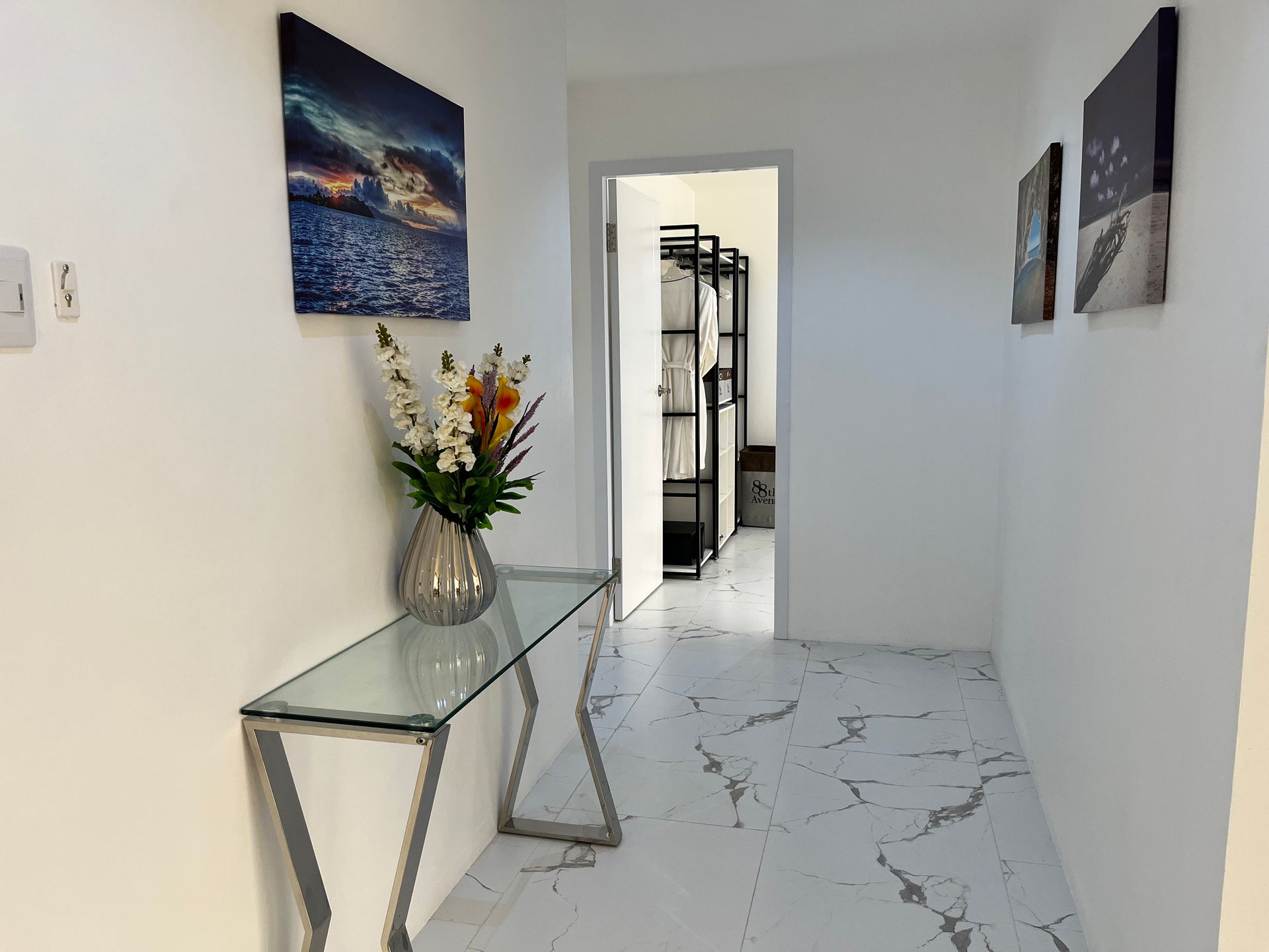 A hallway with a glass table and a vase of flowers on it.