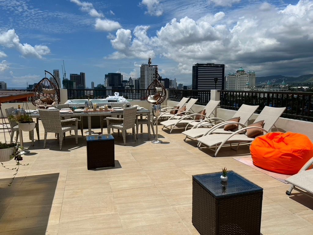 A rooftop patio with tables and chairs and a view of the city