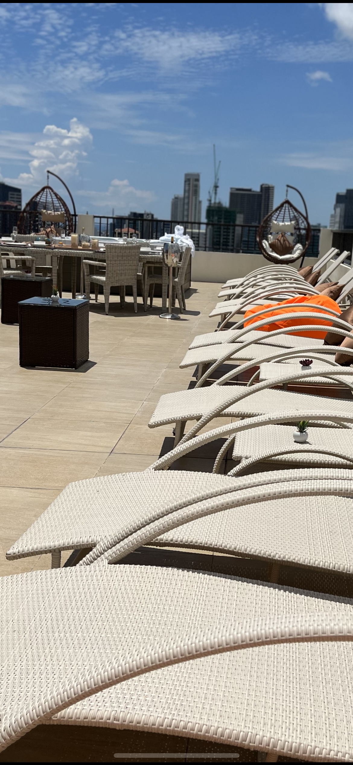 A row of lawn chairs on a rooftop with a city in the background