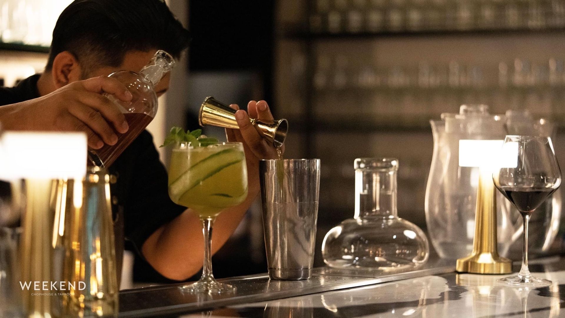 A bartender is pouring a drink into a glass at a bar.