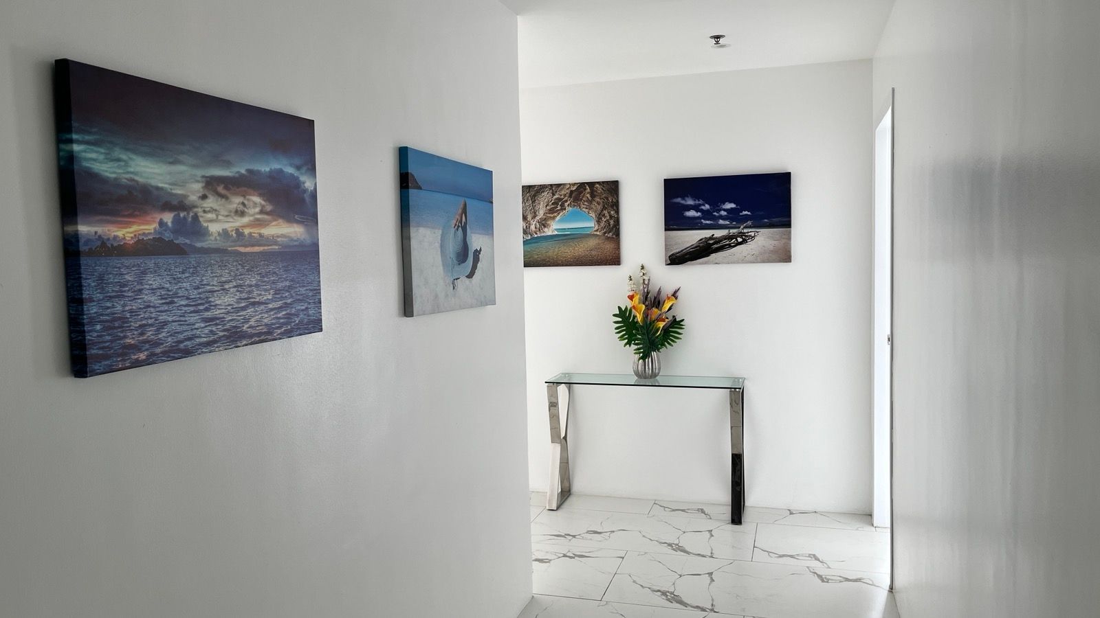 A hallway with a table and paintings on the wall.