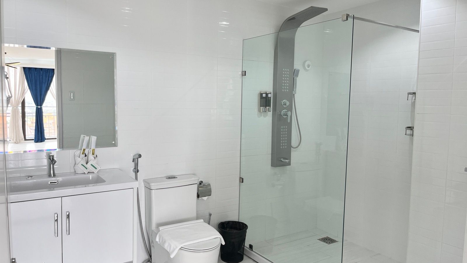 A bathroom with a toilet , sink , shower and mirror.