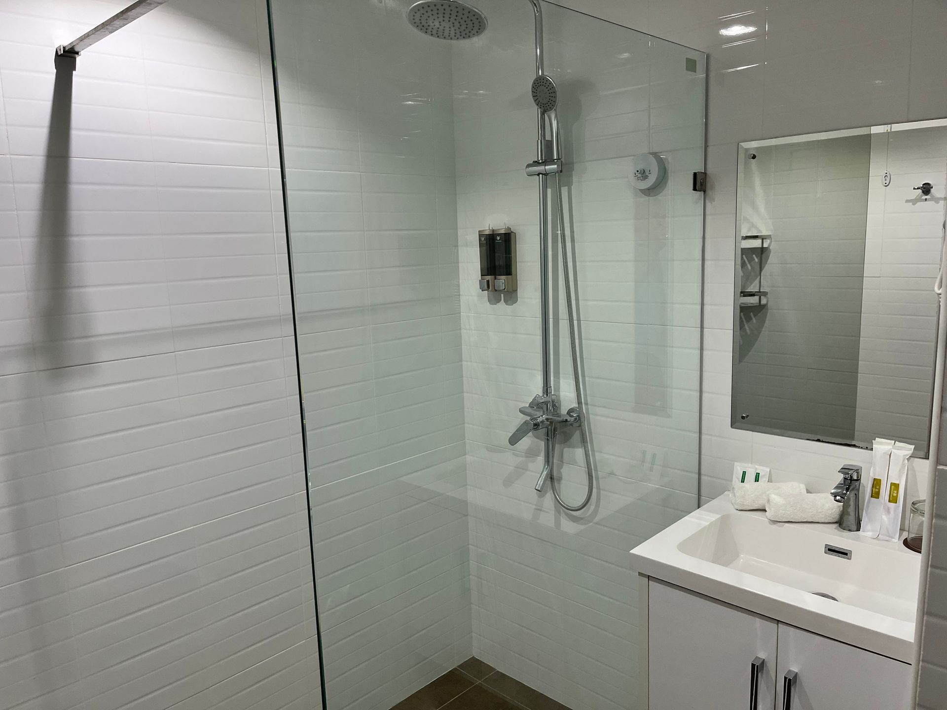 A bathroom with a sink , shower and mirror.