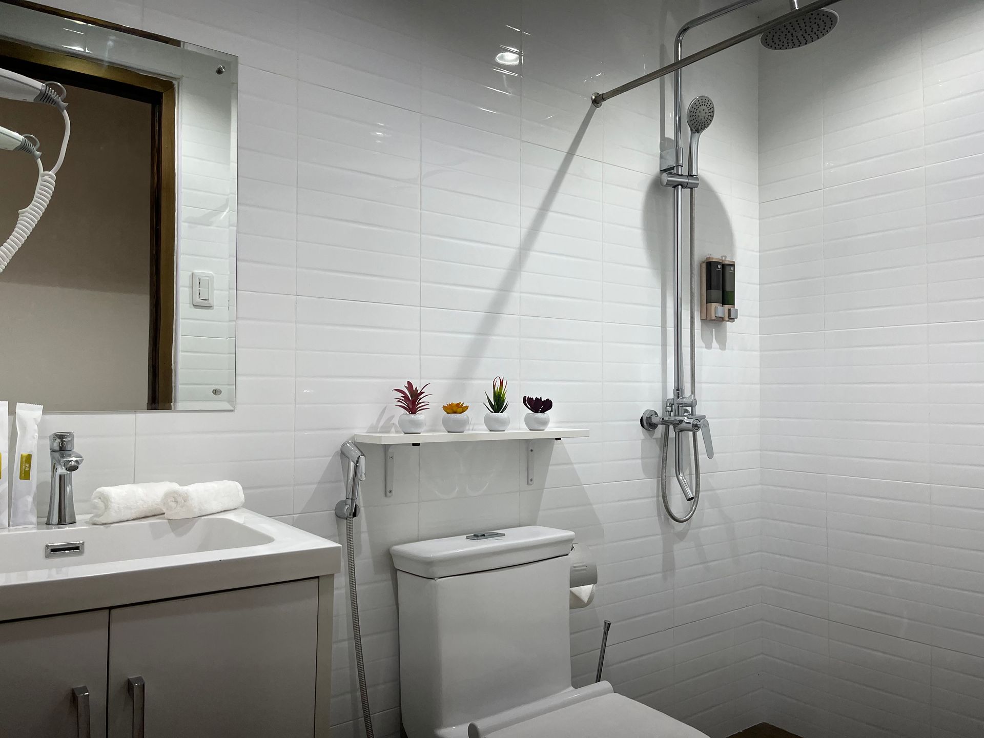 A bathroom with a toilet , sink , mirror and shower.