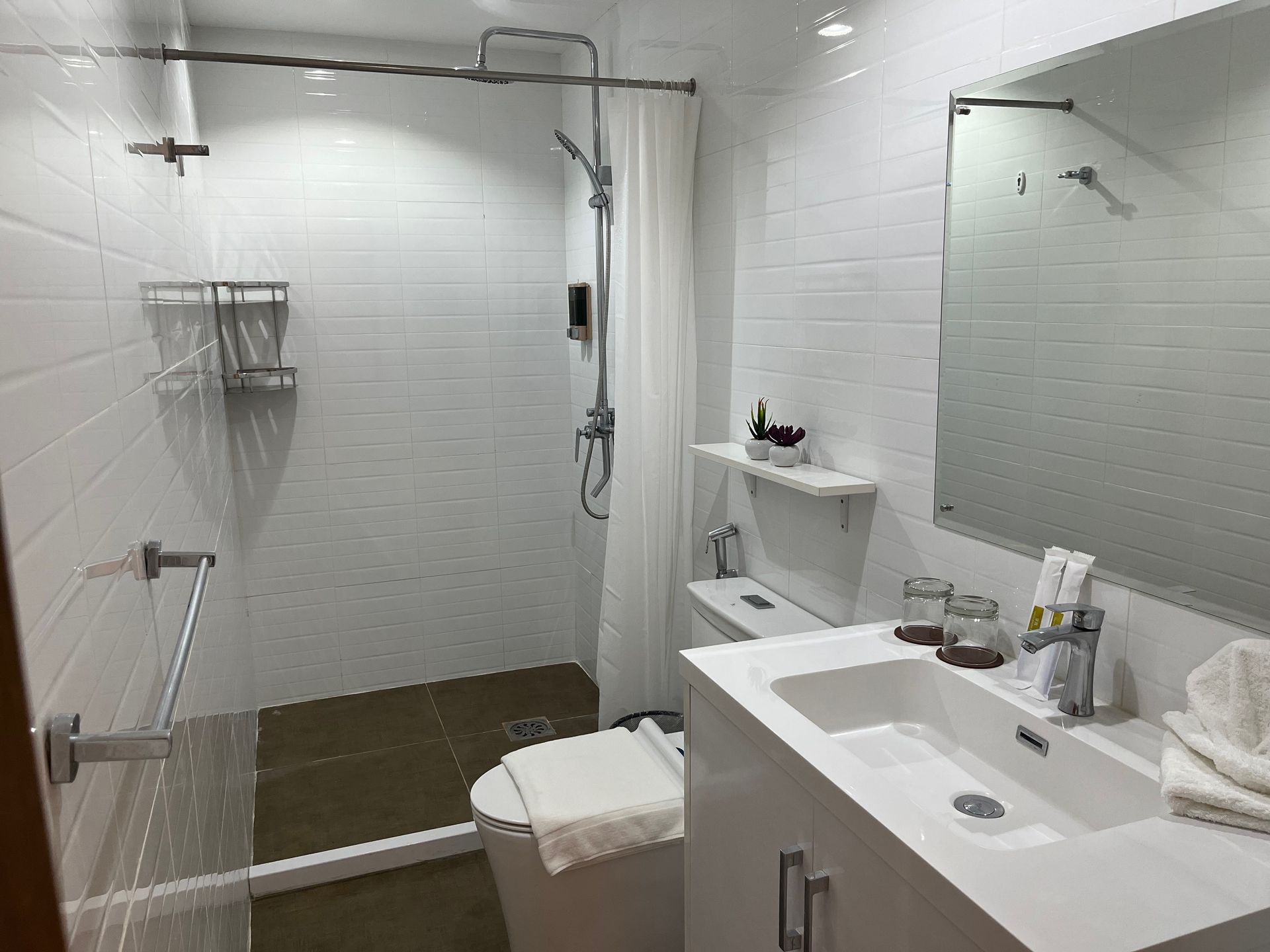 A bathroom with a toilet , sink , mirror and shower.