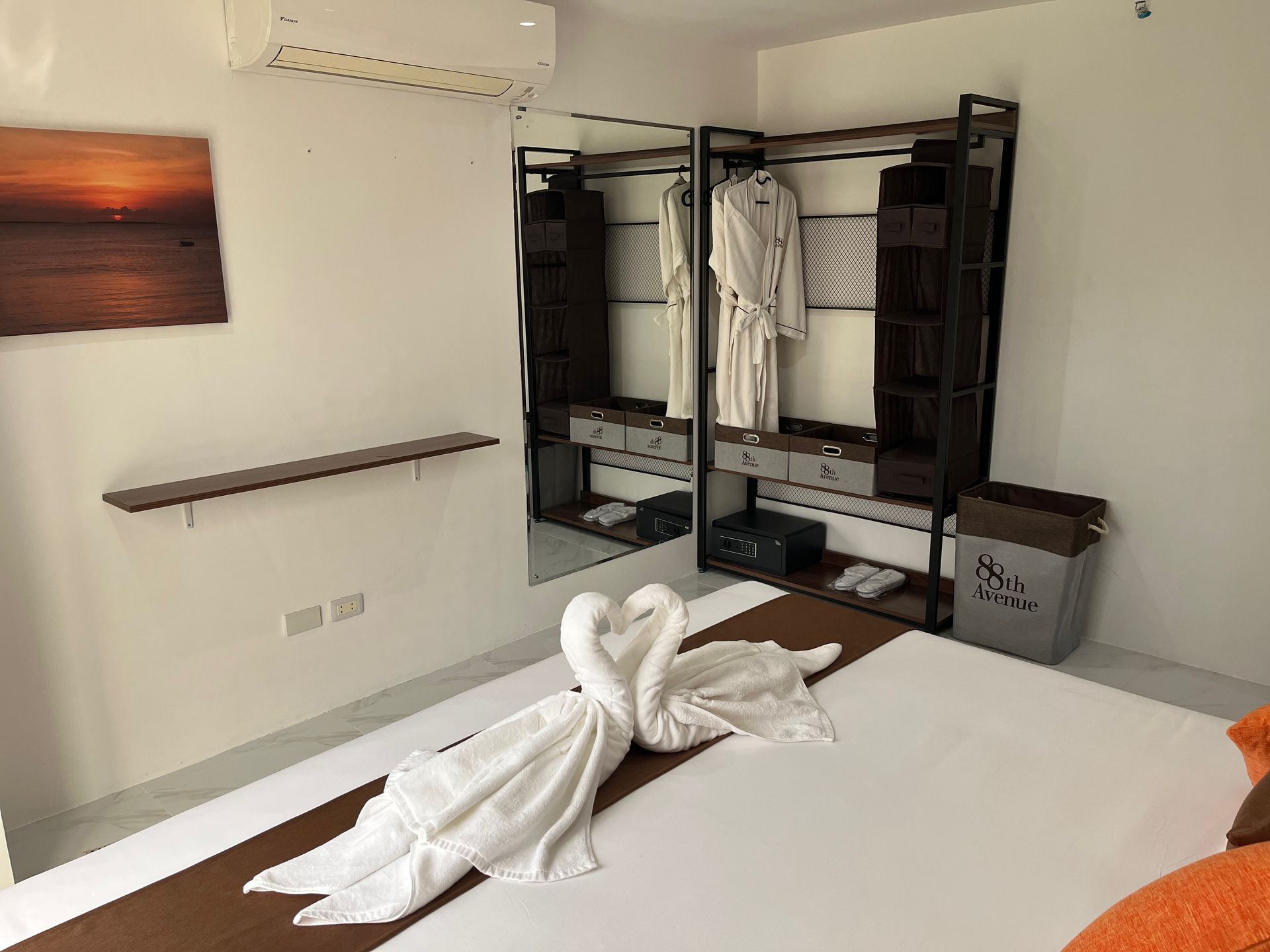 A hotel room with a bed , closet , and swan towels on the bed.