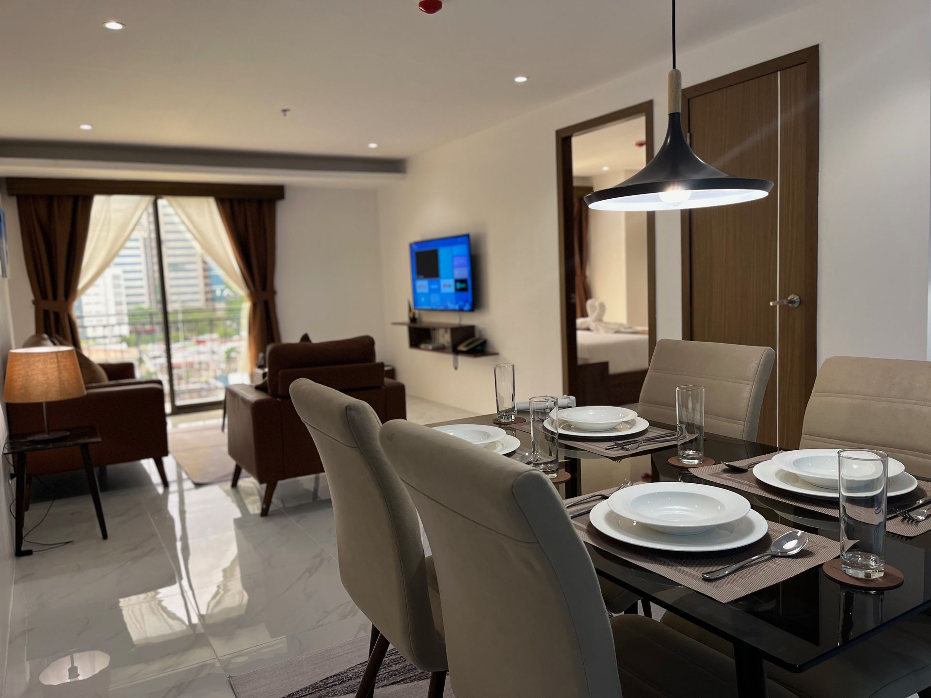 A living room with a dining table and chairs and a flat screen tv.