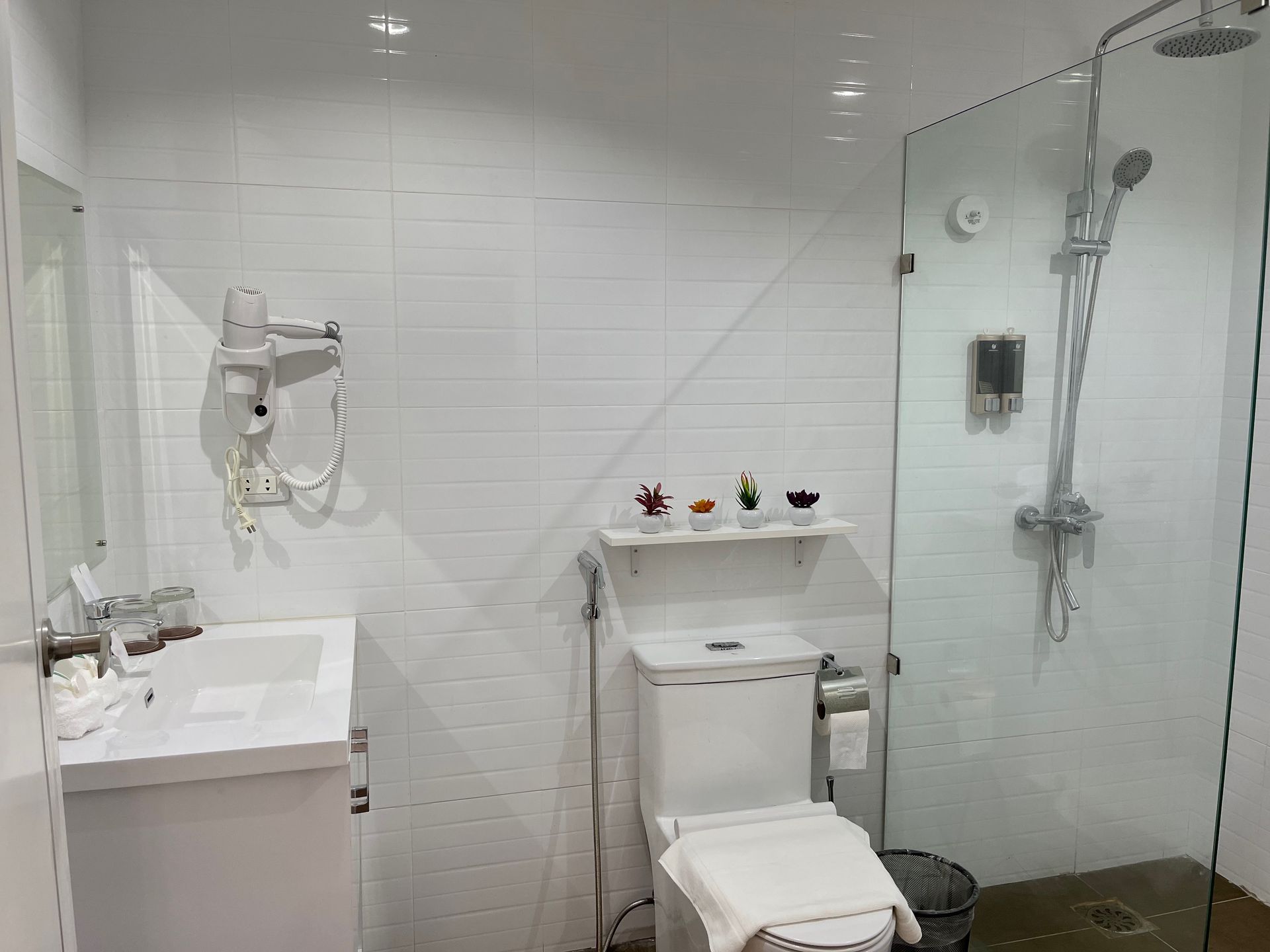 A bathroom with a toilet , sink , shower and mirror.