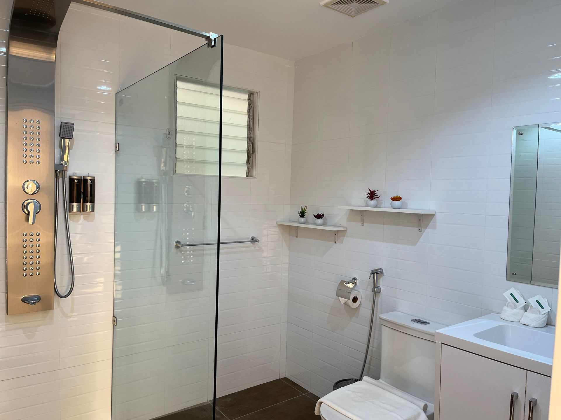 A bathroom with a toilet , sink , shower and mirror.