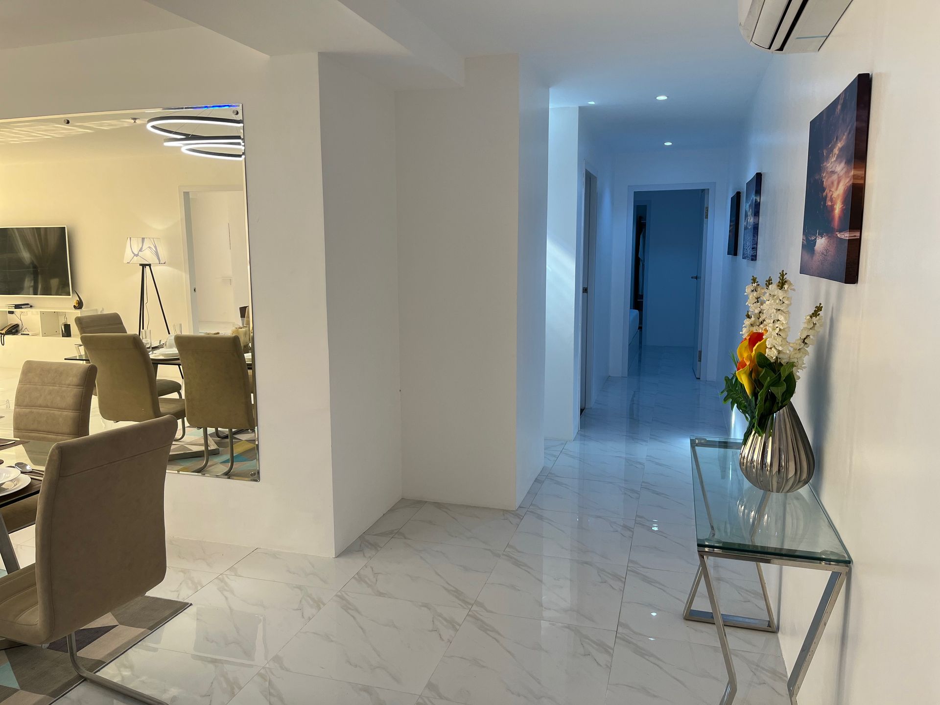 A living room with a table and chairs and a hallway.