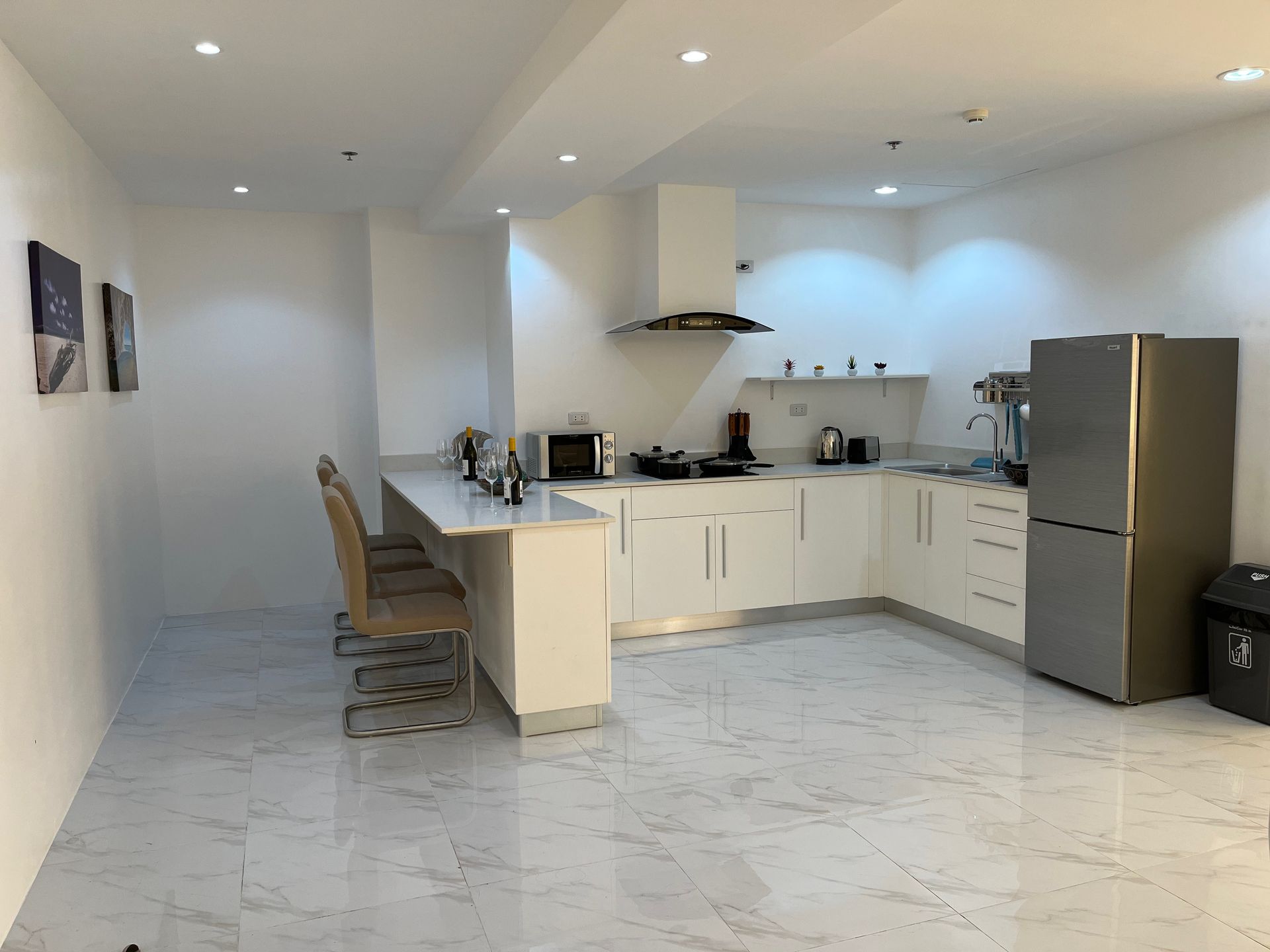 A kitchen with white cabinets and a stainless steel refrigerator.