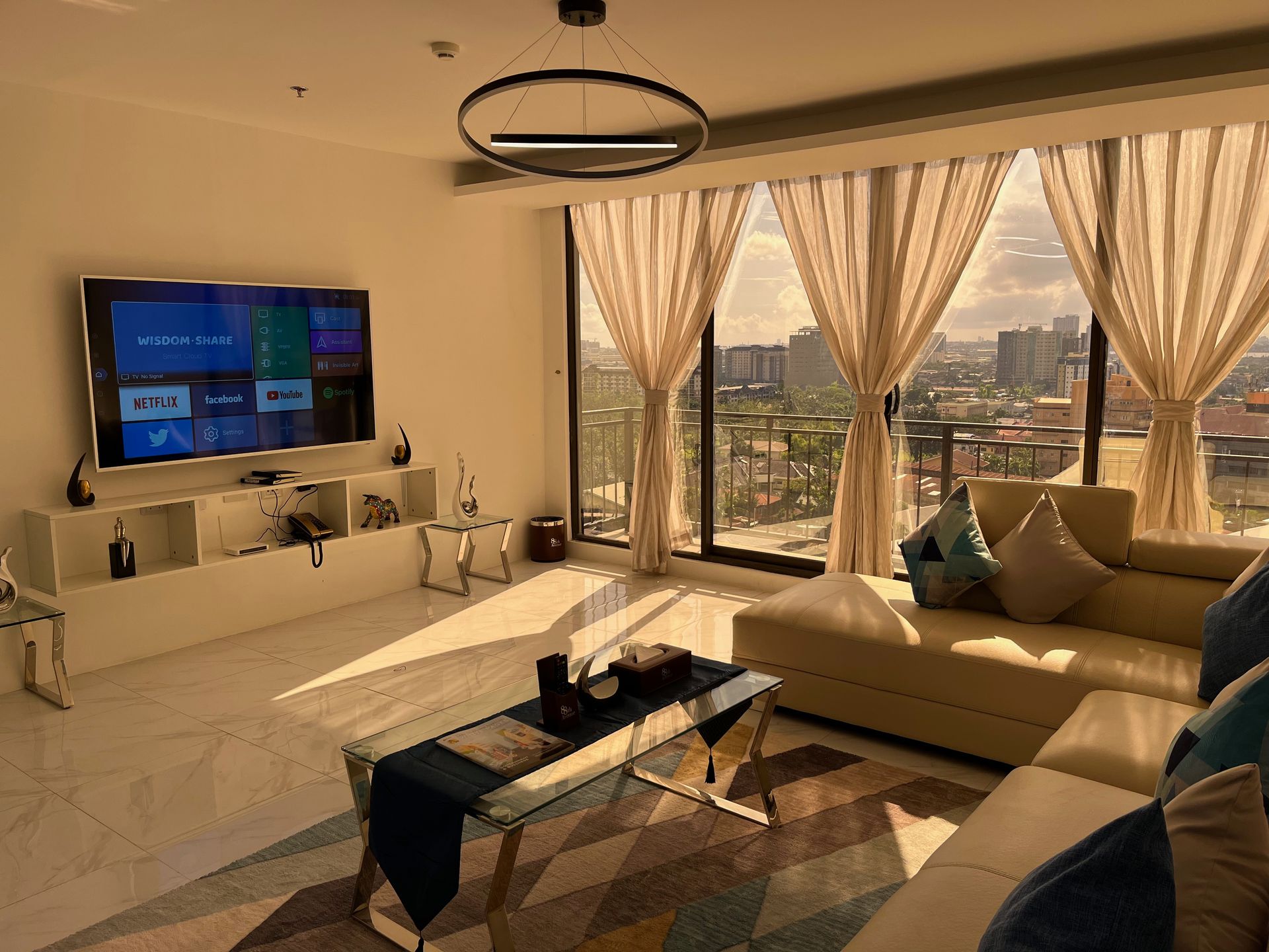 A living room with a couch , television , coffee table and large windows.