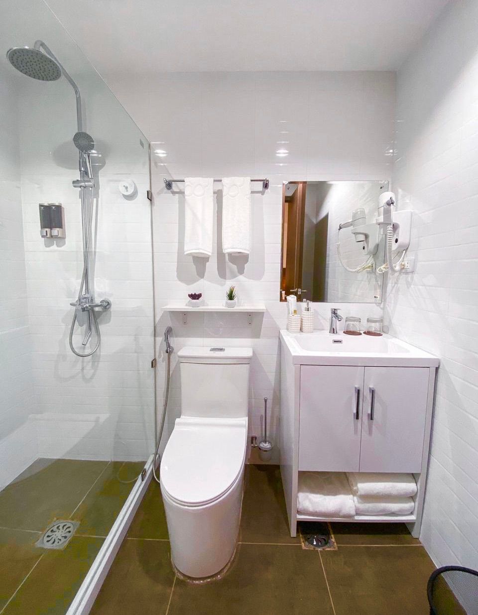 A bathroom with a toilet , sink , shower and mirror.