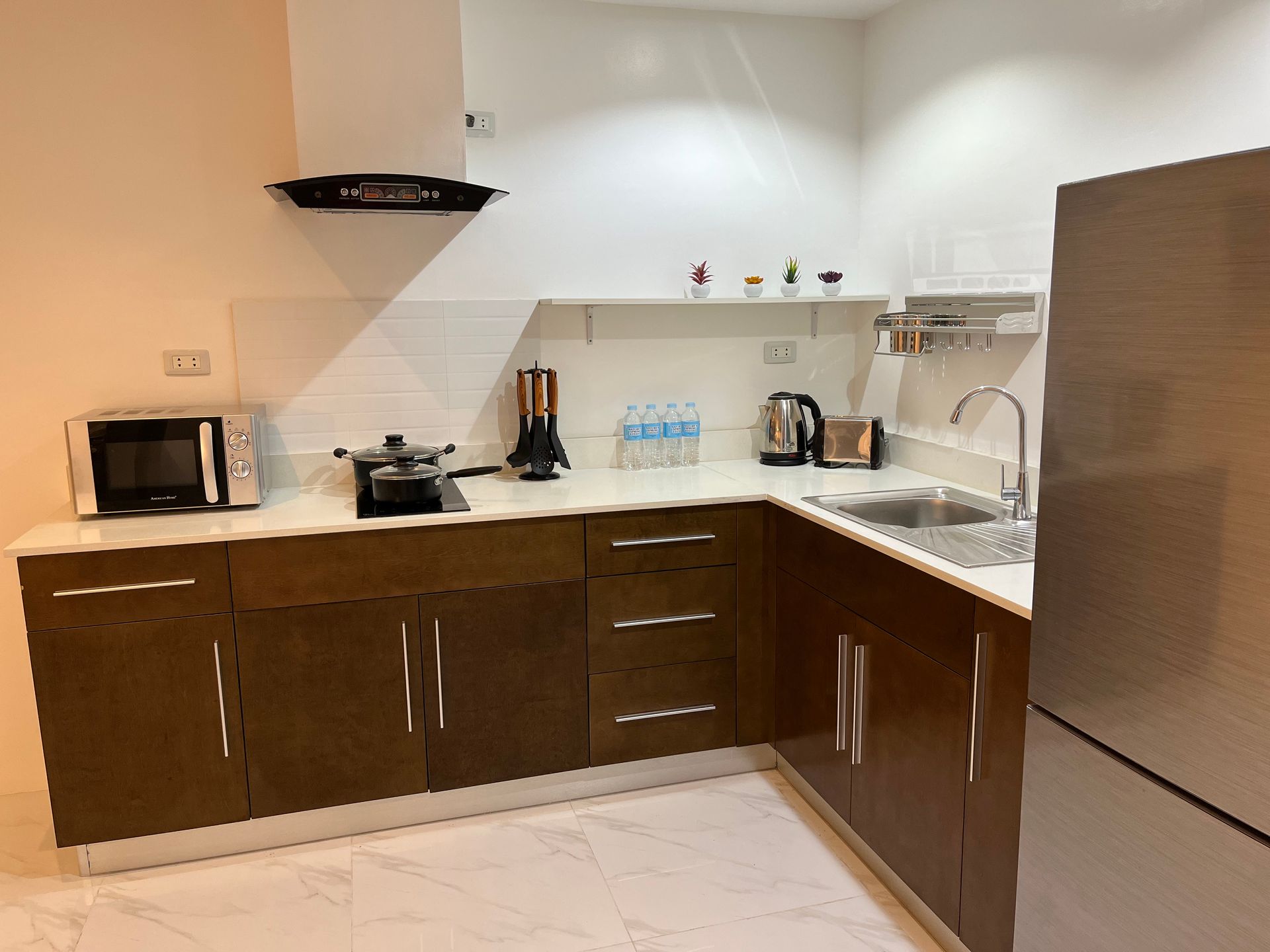 A kitchen with wooden cabinets , a sink , a microwave , and a refrigerator.