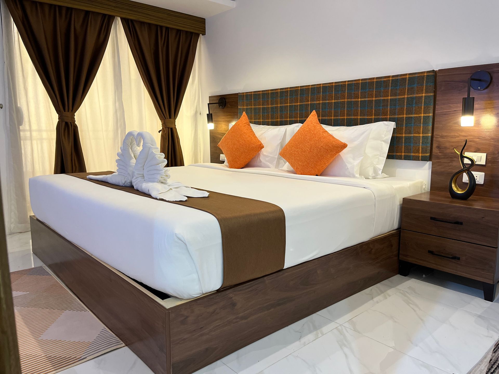 A hotel room with a king size bed and orange pillows.