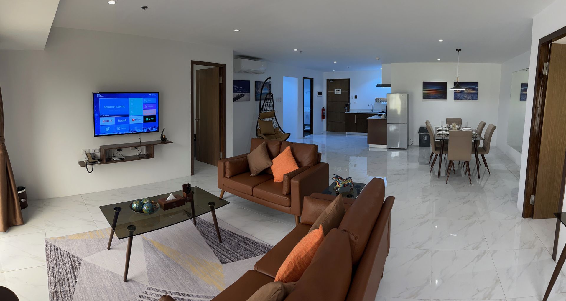 A living room with a brown couch and a flat screen tv on the wall.