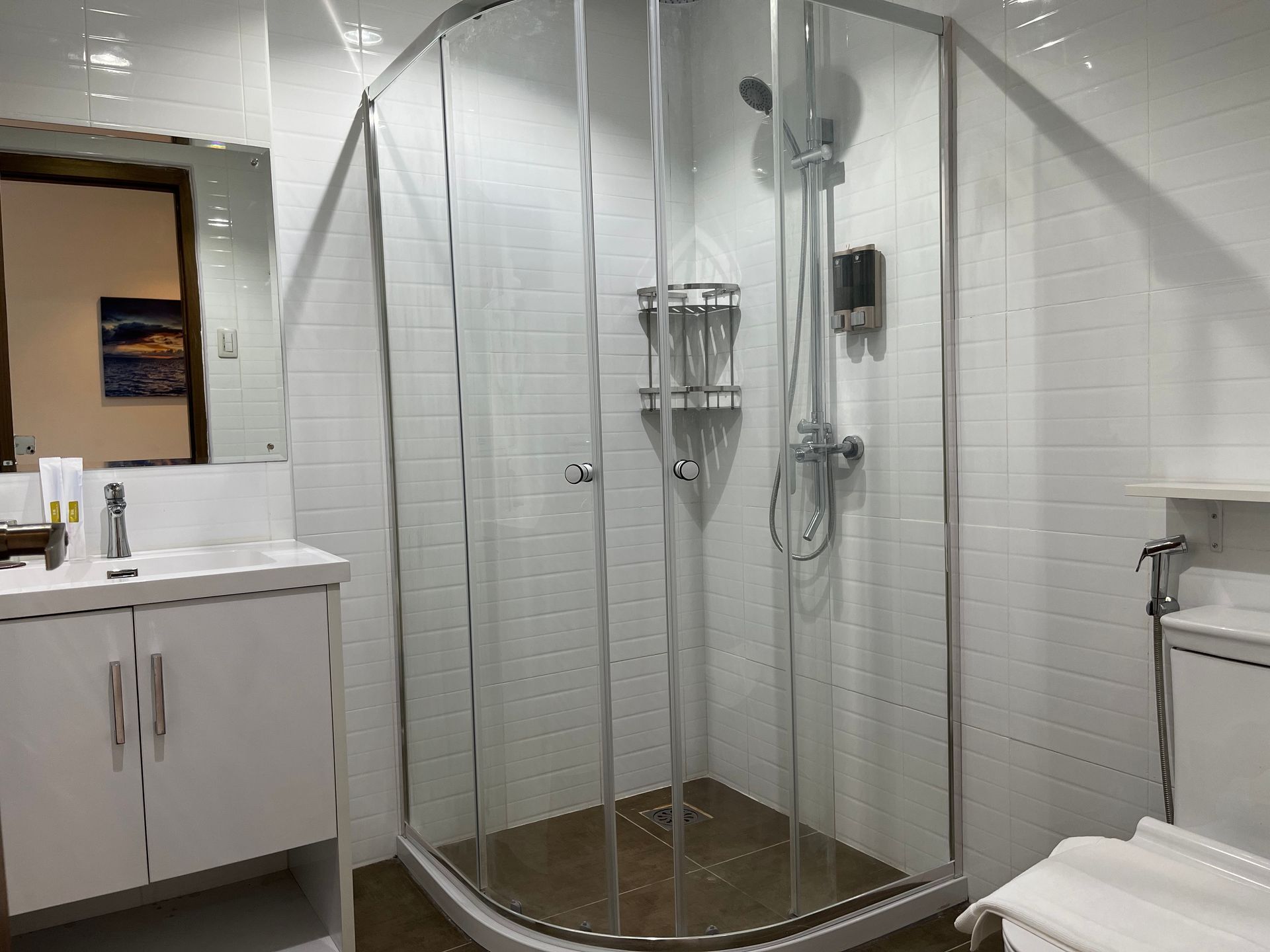 A bathroom with a shower , sink , toilet and mirror.