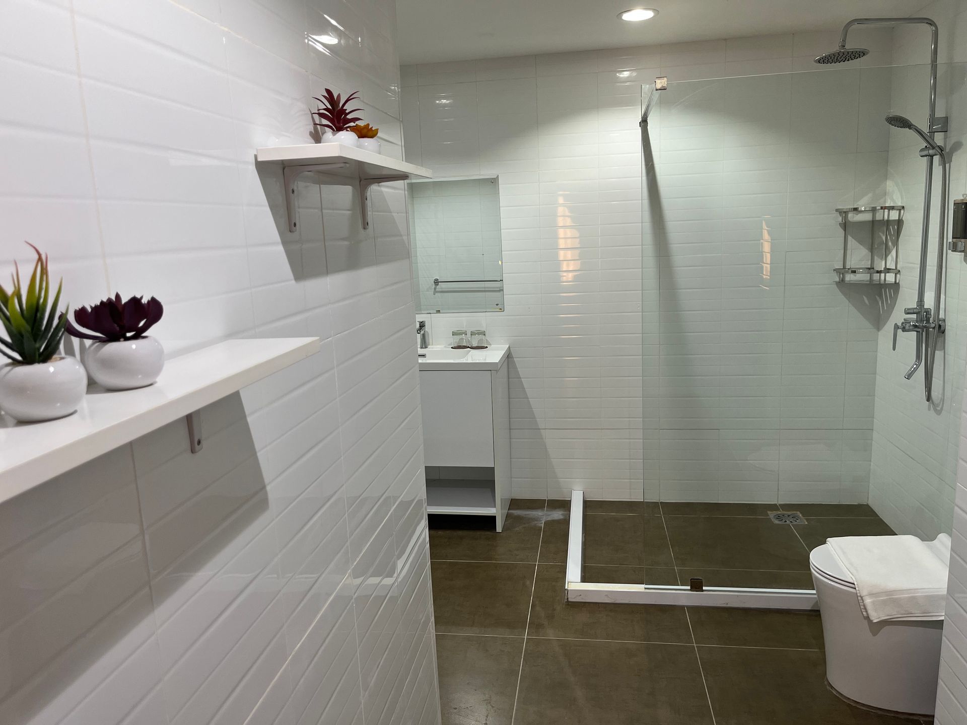 A bathroom with white tiles and a walk in shower