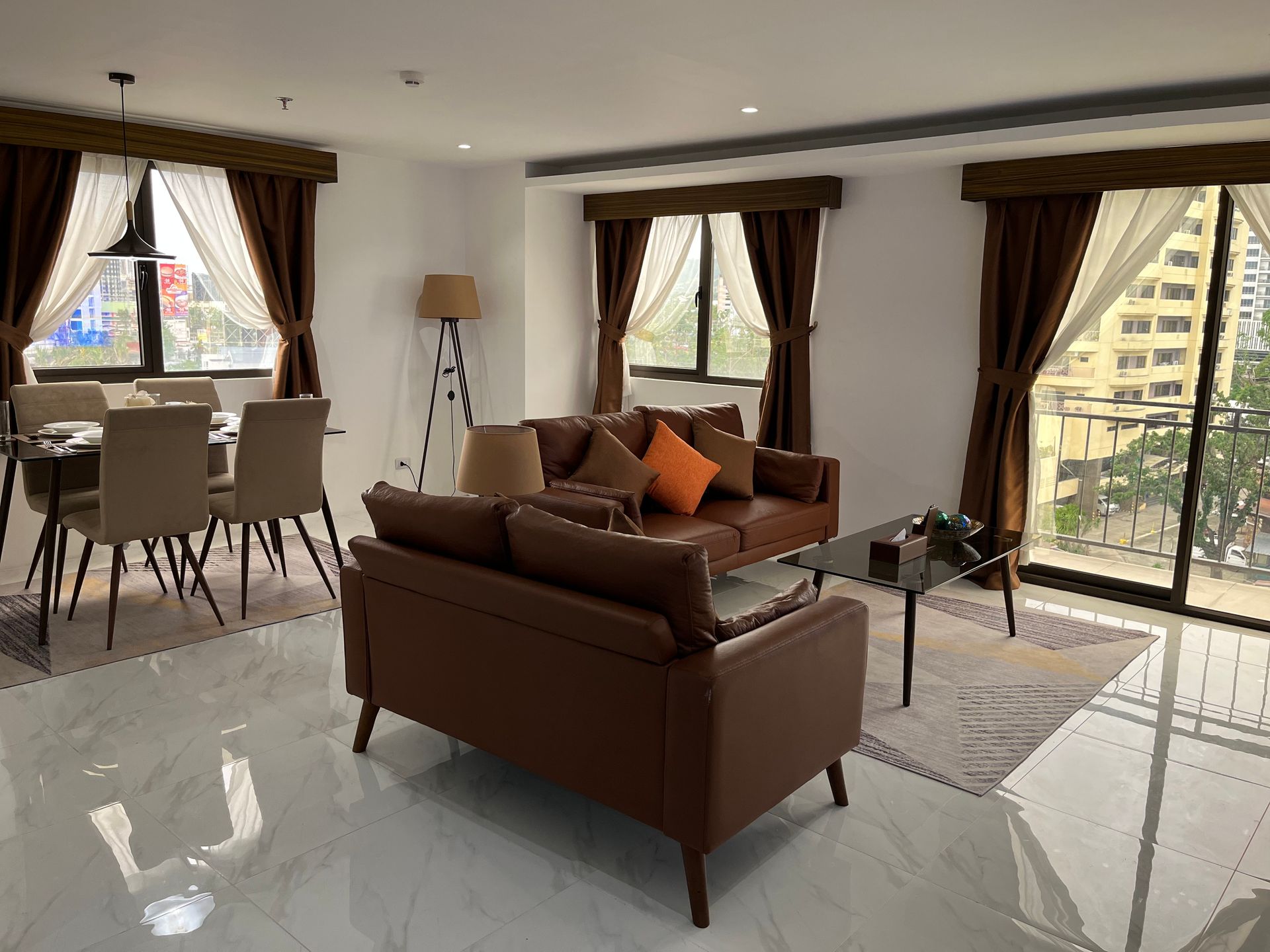 A living room with a couch , table , chairs and windows.