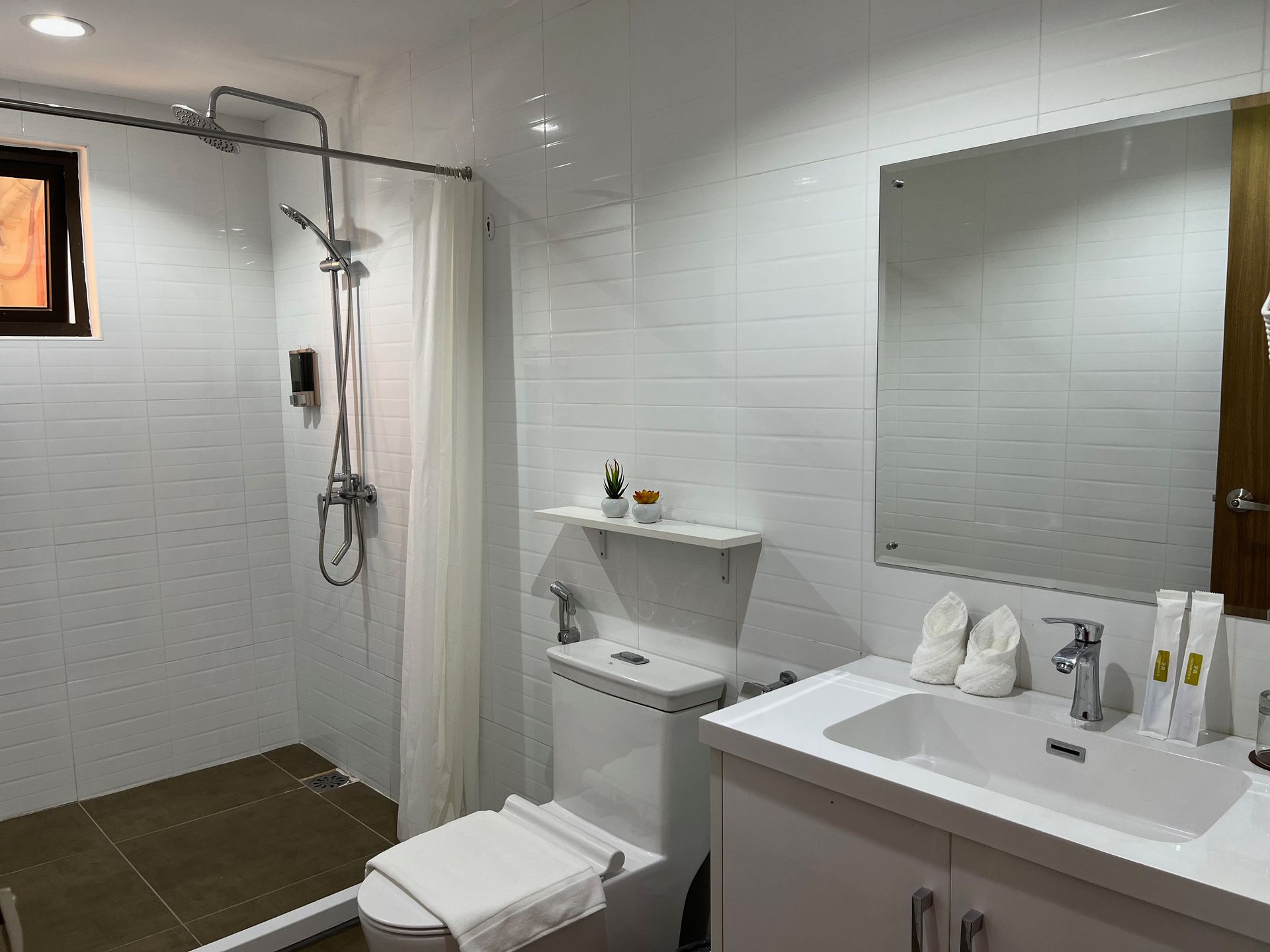 A bathroom with a toilet , sink , shower and mirror.