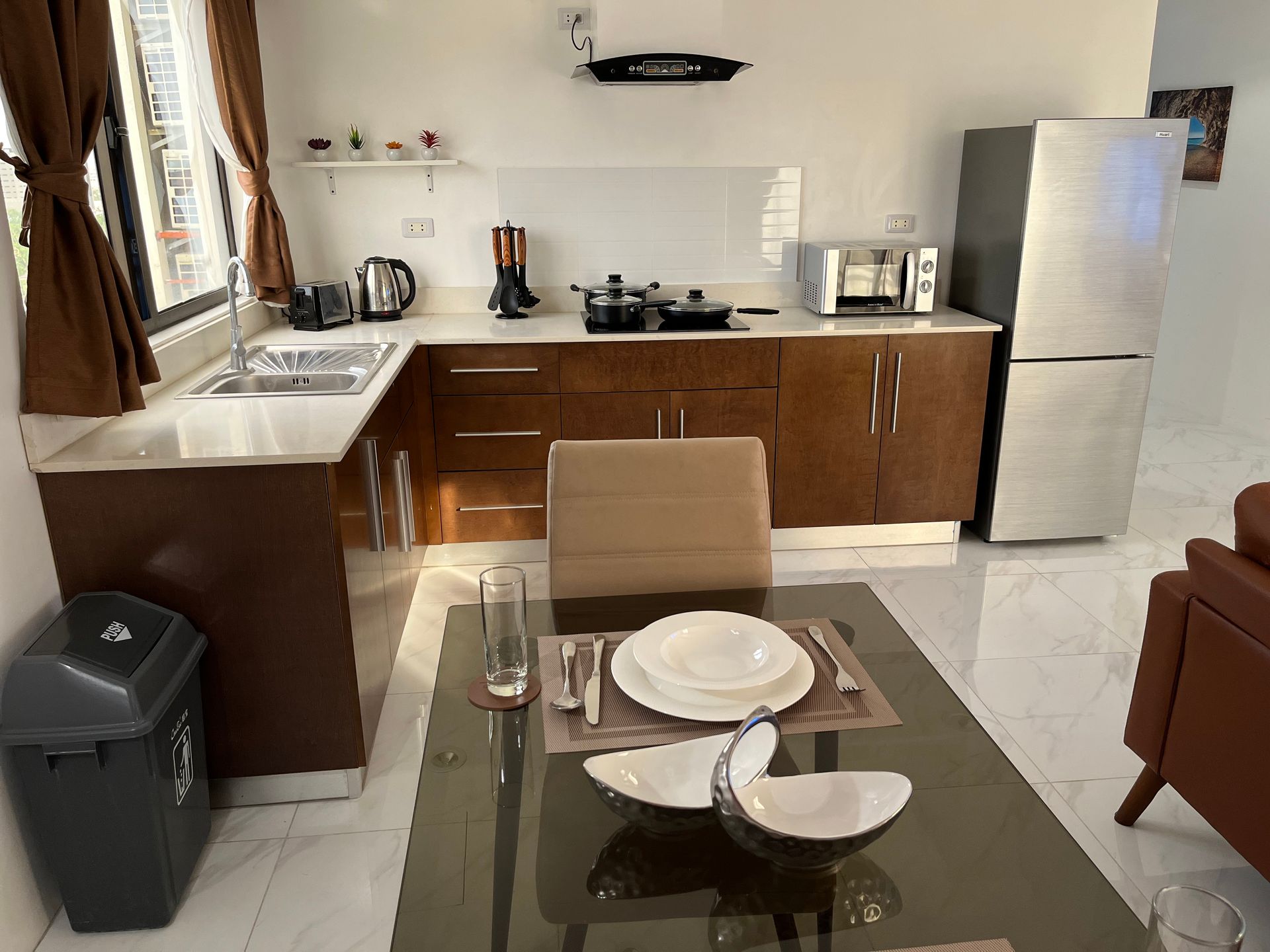 A kitchen with a table and chairs and a trash can