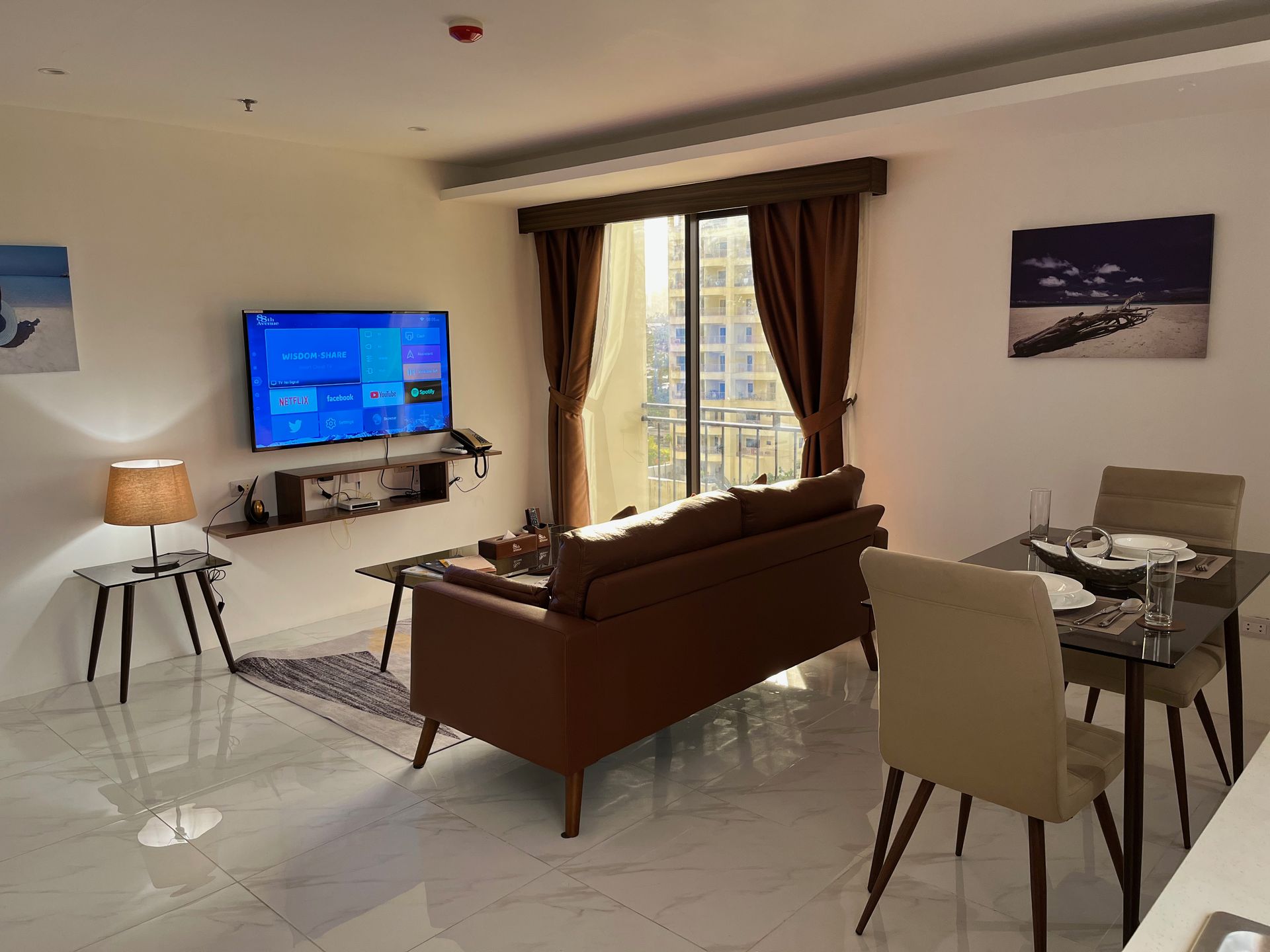 A living room with a couch , table , chairs and a flat screen tv.