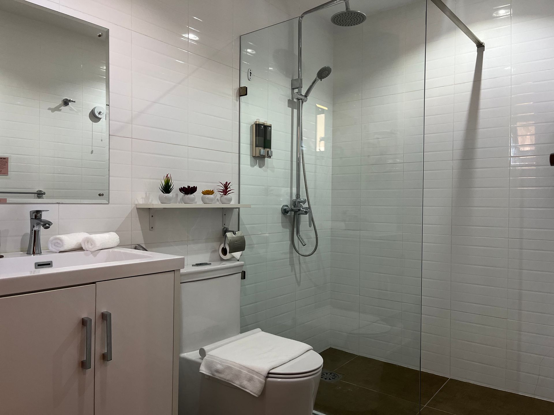 A bathroom with a toilet , sink , mirror and walk in shower.