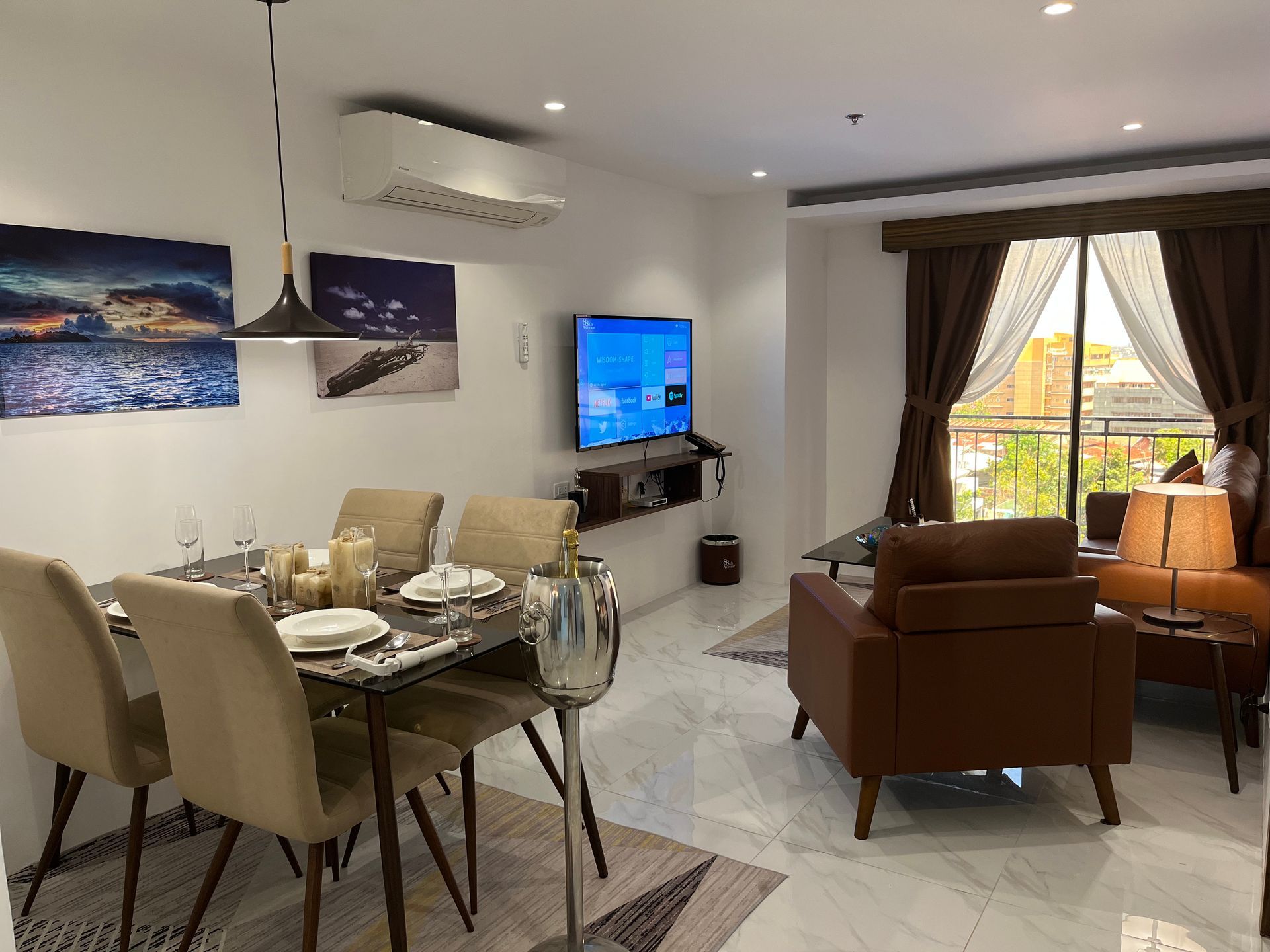 A living room with a dining table and chairs and a flat screen tv.