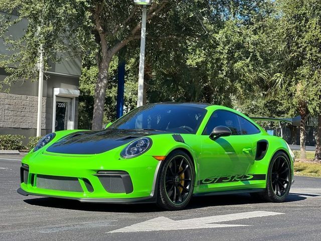 a green porsche 911 gt3 rs is parked in a parking lot .