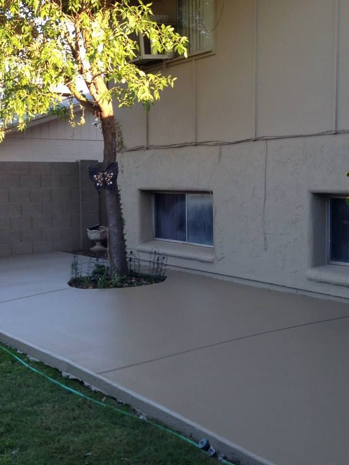 Concrete patio next to a beige building with a tree growing through it.