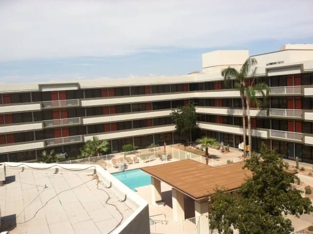Hotel courtyard with a pool, surrounded by multi-story buildings, under a cloudy sky.