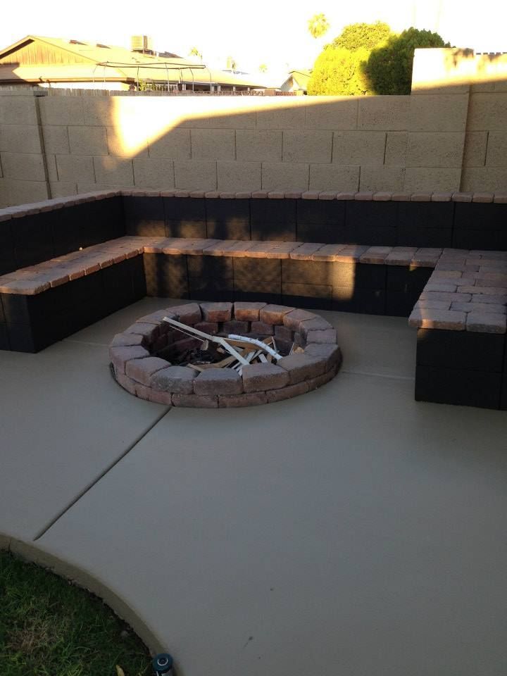Outdoor patio with fire pit and built-in seating. Tan and brown tones. Concrete floor.
