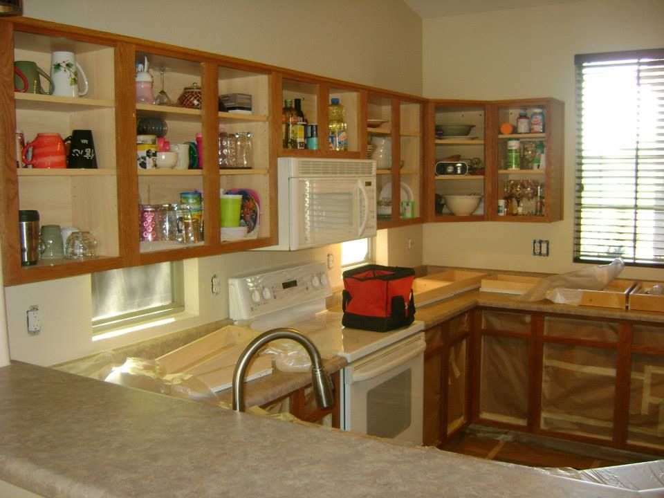Kitchen with oak cabinets, a white microwave, and countertop. Cabinets are partially empty.