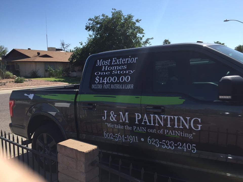 Black truck with J&M Painting logo parked in front of a home. Offers exterior home painting for $1400.