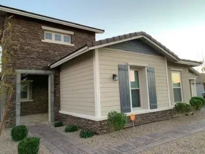Beige and brown house with stone facade and blue shutters.