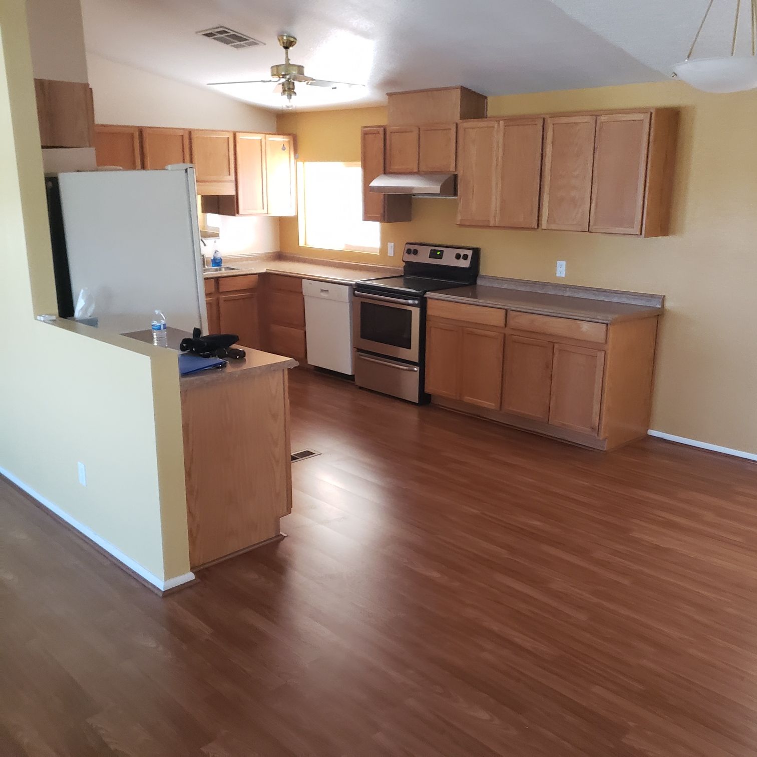 Kitchen with wooden cabinets, stainless steel appliances, and brown laminate flooring.